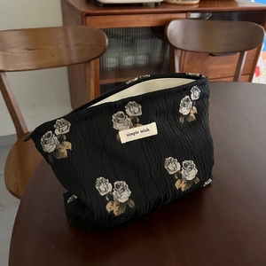 Close-up of black jacquard fabric cosmetic bag with rose embroidery and zipper detail