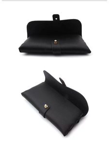 Detail of black pebbled leather eyeglass pouch with gold snap button and soft texture