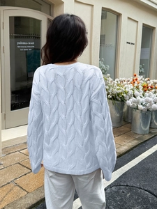 Street style view of light blue cable knit sweater featuring classic texture on the back