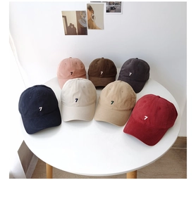 Top view of seven colorful cotton baseball caps with embroidered number seven on a table