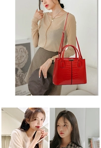 Detail of red crocodile pattern handbag with dual handles and golden hardware