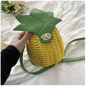 Detail of hand-woven pineapple-shaped bucket bag with green leaf lid and gold twist lock