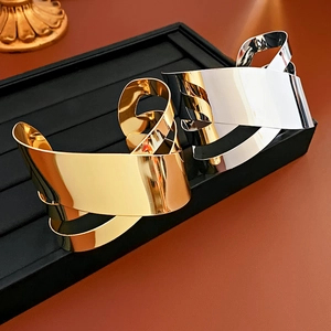 Detail showing irregular twisted metal cuffs in gold and silver finishes on black stand
