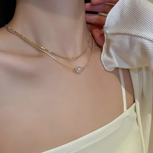 Close-up of golden layered necklace with shimmering iridescent pearl charm on model
