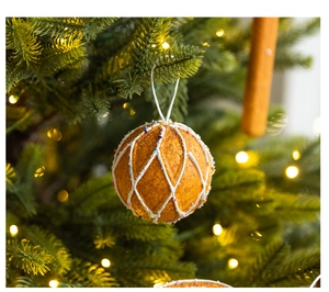 Close-up of orange peel texture Christmas ornament with beads on a glowing pine tree