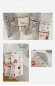 Detailed view of grey and ivory mesh crew socks featuring star and apple patterns