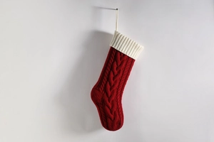 Detail of red cable knit Christmas stocking with creamy white ribbed cuff and hanging loop