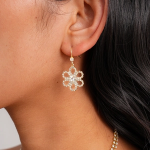 Close-up of gold-plated flower earrings with shimmering white cubic zirconia stones