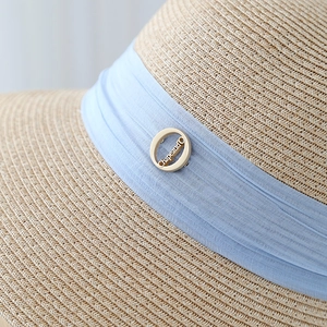 Macro shot of fine straw weave with blue ribbon and engraved gold logo buckle