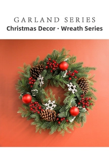 Detail of snowy Christmas wreath with pine cones and red berries on orange backdrop
