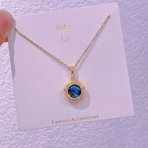Dettaglio della collana dorata con pendente galassia blu e pietre in zircone lucido