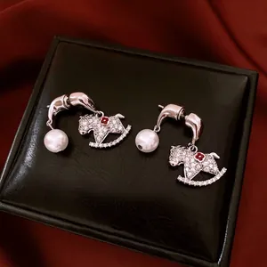Boucles d'oreilles cheval à bascule plaquées or avec diamants et perles sur velours