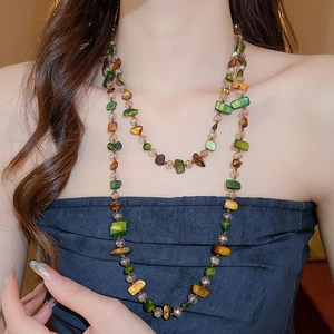 Close-up of double-layer beaded necklace with irregular green and amber stones