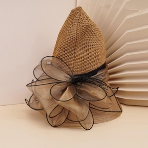 Close-up of woven straw sun hat with champagne organza bow and black trim detail