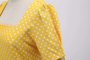 Detail of square neckline and puff sleeves on yellow polka dot retro style midi dress