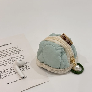 Detail view of mint green quilted earphone pouch with gold zipper and pearl charm