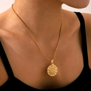 Detailed close-up of golden sun totem pendant with twist chain worn on neck