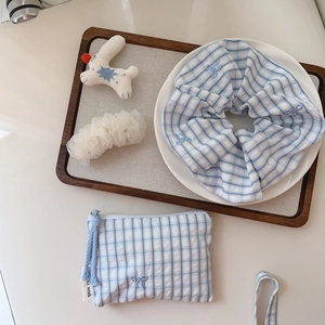 Close-up of blue plaid cotton fabric accessories with bow embroidery and zipper pouch