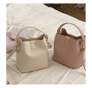 Detail of minimalist bucket bags in beige and pink colors with gold hardware and logo