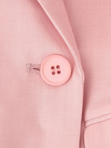 Dettaglio di un blazer rosa con tessuto a trama piatta e bottone a quattro fori