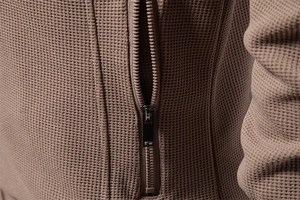 Macro shot of apricot waffle knit fabric and high-quality zipper detail for men jacket