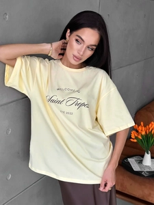 Close-up of a loose light yellow cotton T-shirt featuring Saint Tropez graphic print