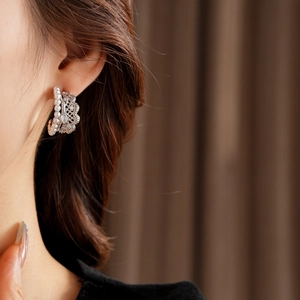 Close-up of vintage lace pearl C-shaped earrings with zircons worn by a model