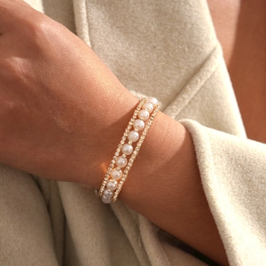 Close-up of elegant gold triple-layer bracelet featuring white pearls and zircon crystals