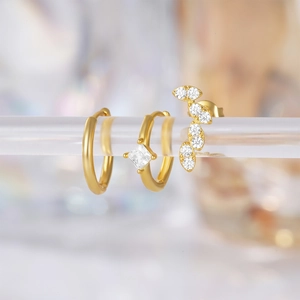 Macro shot of 925 silver gold-plated earring set with square zircon and leaf stud