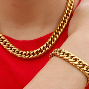 Men's bold golden stainless steel Cuban link necklace and bracelet set on model