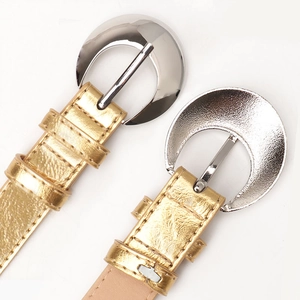 Fashionable gold leather belts with silver crescent buckles on a white background