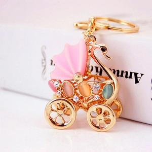Golden stroller keychain with pink canopy and colorful rhinestones on white background