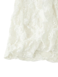 Close-up detail of high-density floral lace knit pattern on elegant white top