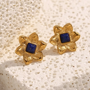 Detail of 18K gold flower stud earrings with a square blue gemstone on coral stone