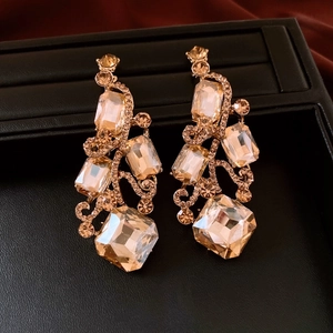Detailed view of champagne crystal drop earrings with geometric cuts on black leather