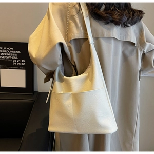 Detail view of a cream white PU leather bucket bag showing soft texture and side strap design