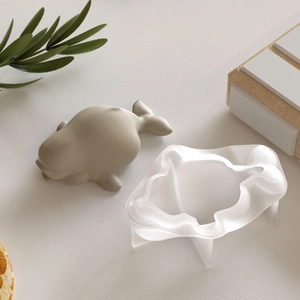 DIY silicone mold with whale sculpture on a minimalist textured surface with dried citrus