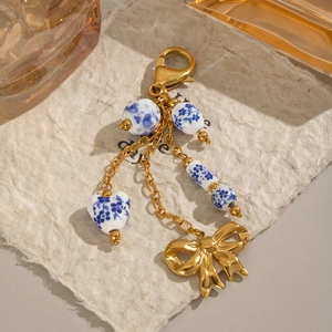 Détail du porte-clés doré avec perles en céramique bleues et pendentif nœud miroir