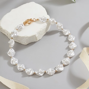 Detail of baroque pearl necklace with gold beads and T-bar toggle clasp on stone