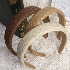 Three woven wide headbands in brown, khaki, and beige colors on a lace tablecloth