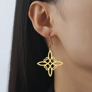 Goldene Hexenknoten-Ohrringe mit Quasten an einem weiblichen Modell für Boho-Look
