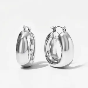 Close-up of silver oval U-shaped hoop earrings with a polished hollow geometric design