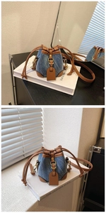Detail of denim bucket bag with brown leather trim and golden drawstring hardware