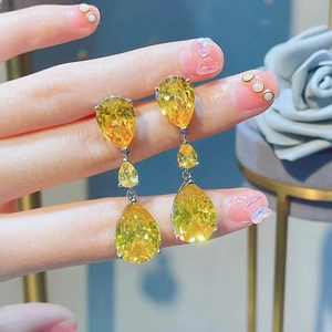 Detailed close-up of yellow teardrop-shaped drop earrings with three-tier crystal stones