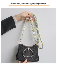 Detail of vintage black purse with silver heart clasp and colorful floral macrame strap