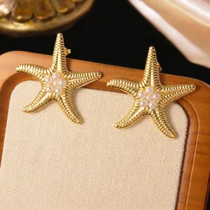 Close-up of golden starfish earrings with white pearls on a display stand