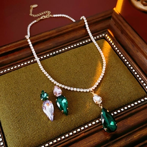 Detailed view of emerald and lavender teardrop zircon jewelry set on green velvet