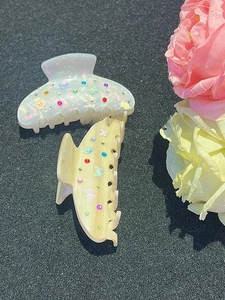 Dettaglio di fermagli a farfalla con strass colorati in bianco e giallo crema