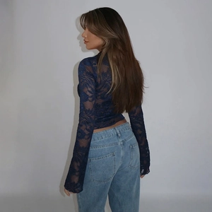 Detailed back view of a slim-fit dark blue lace long-sleeve top paired with blue jeans