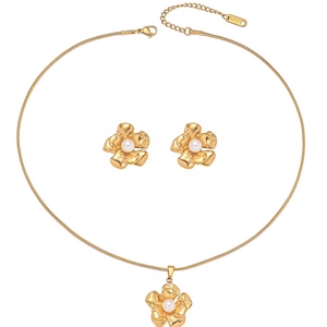 Detail of gold stainless steel camellia necklace and pearl earrings jewelry set